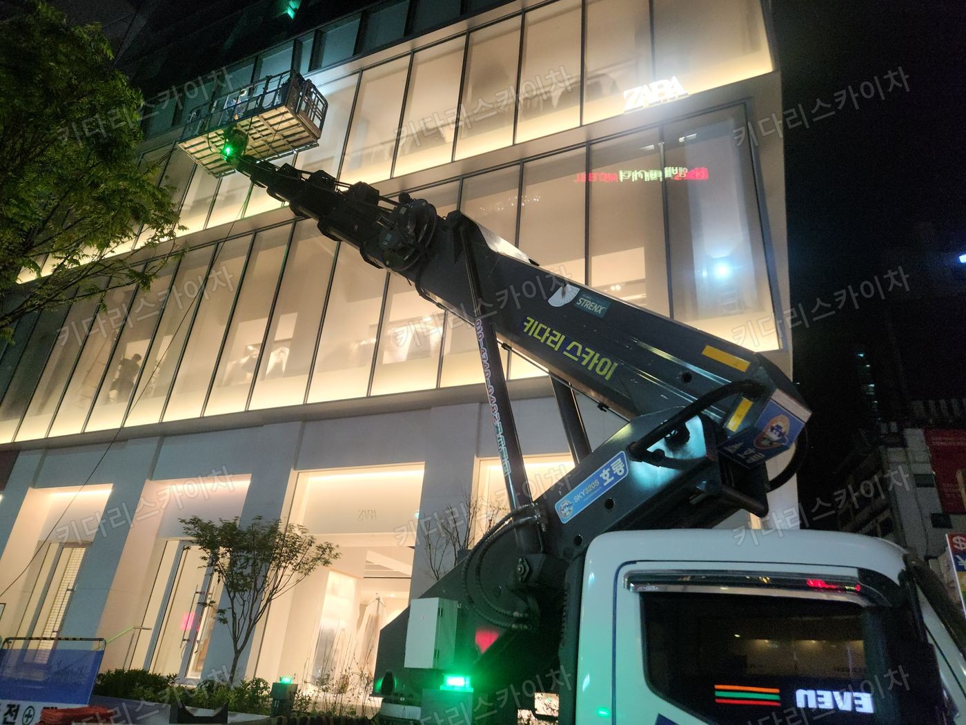 조명이 켜진 상가 외벽 앞 야간 장비 배치