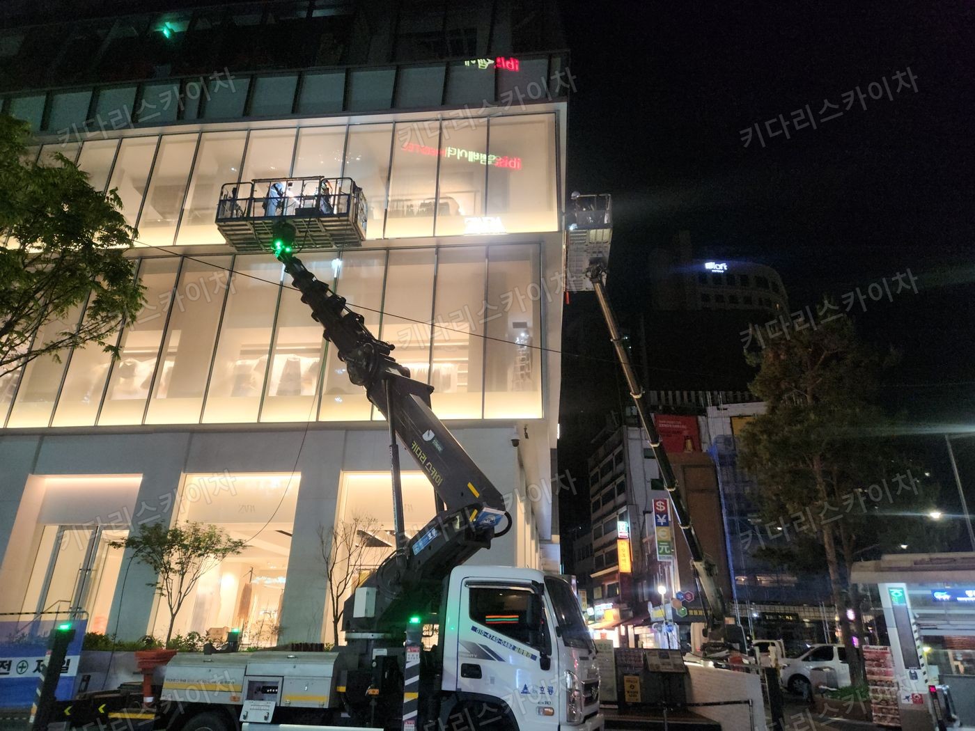 조명이 켜진 상가 외벽 앞 야간 장비 배치