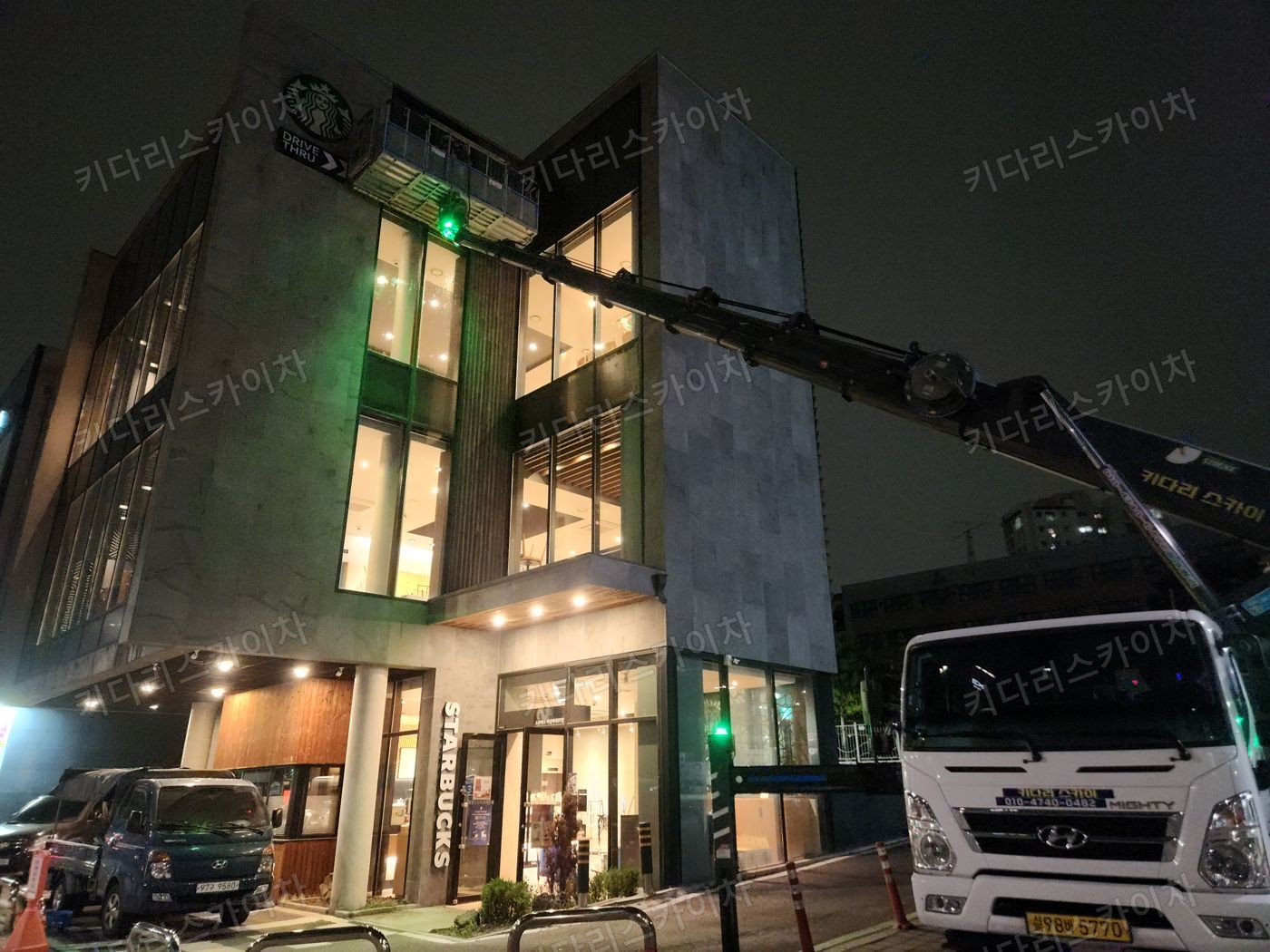 조명이 켜진 상가 외벽 앞 야간 장비 배치