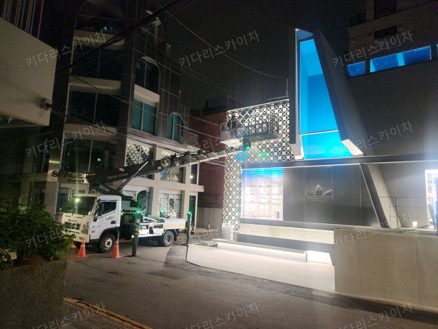 조명이 켜진 상가 외벽 앞 야간 장비 배치
